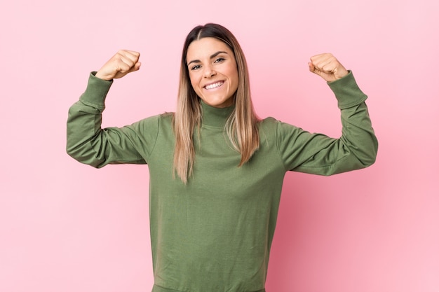 Jovem mulher caucasiana isolada mostrando o gesto de força com os braços, símbolo do poder feminino