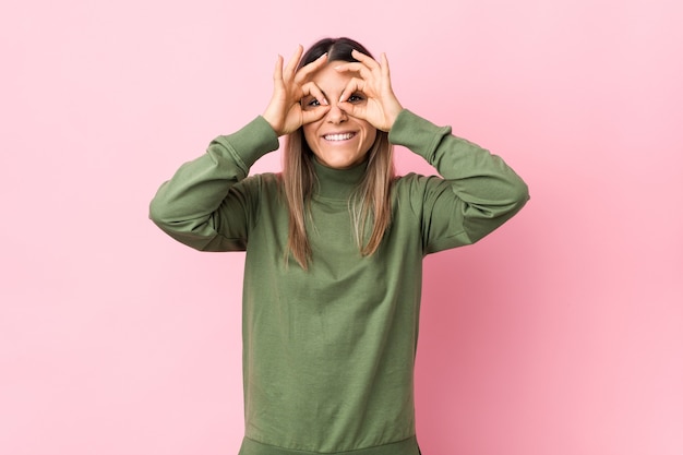 Jovem mulher caucasiana isolada mostrando sinal positivo sobre os olhos