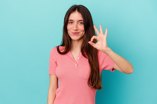 Jovem mulher caucasiana isolada na parede azul alegre e confiante, mostrando o gesto de ok.