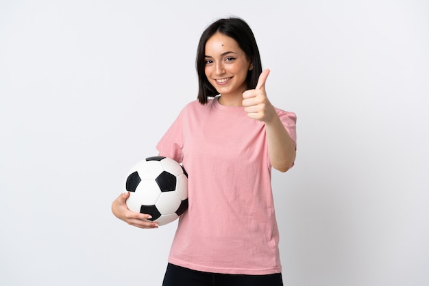 Jovem mulher caucasiana isolada na parede branca com bola de futebol e polegar para cima