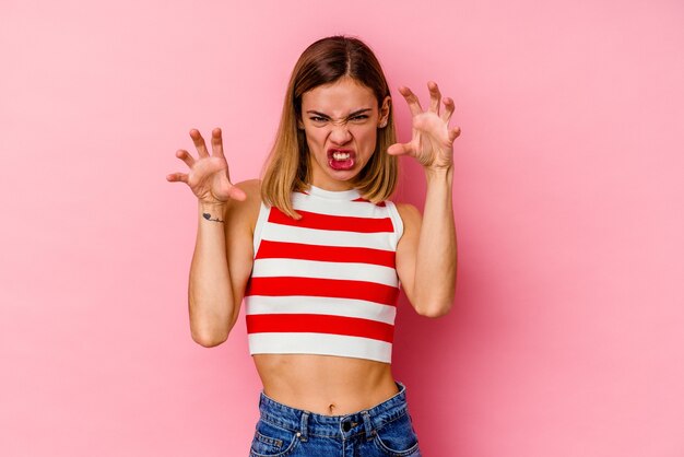 Jovem mulher caucasiana isolada na parede rosa mostrando garras imitando um gato, gesto agressivo