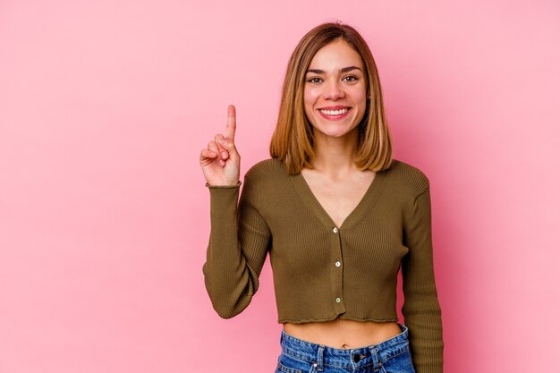 Jovem mulher caucasiana isolada na parede rosa mostrando o número um com o dedo