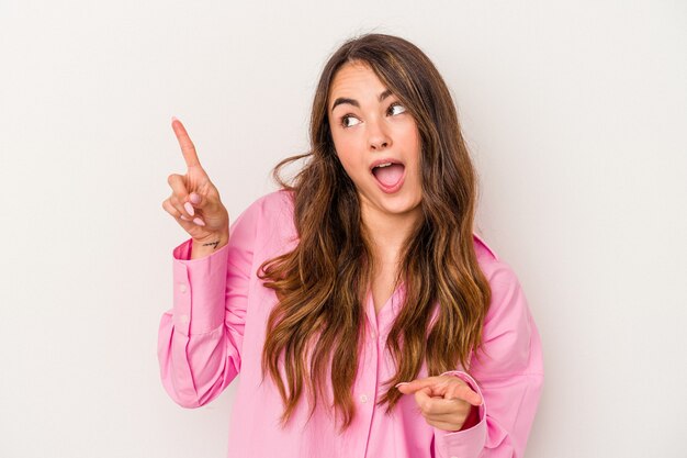 Jovem mulher caucasiana, isolada no fundo branco, apontando para diferentes espaços de cópia, escolhendo um deles, mostrando com o dedo.