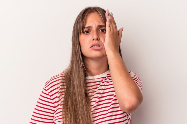 Jovem mulher caucasiana, isolada no fundo branco, cansada e com muito sono, mantendo a mão na cabeça.