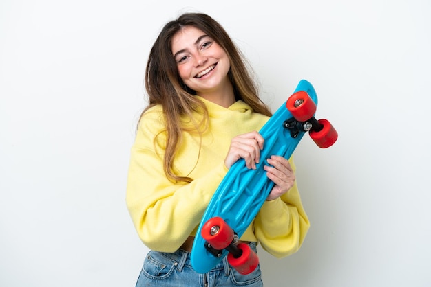 Jovem mulher caucasiana isolada no fundo branco com um skate com expressão feliz