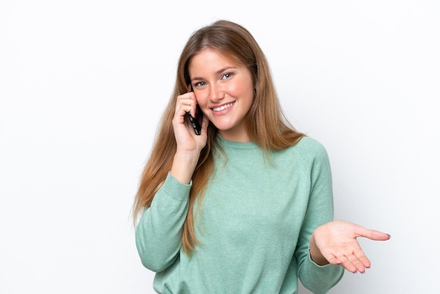 Jovem mulher caucasiana, isolada no fundo branco, conversando com alguém ao telefone celular