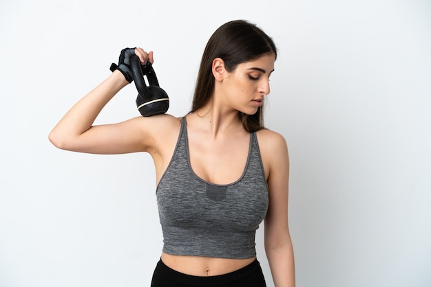 Jovem mulher caucasiana isolada no fundo branco fazendo halterofilismo com kettlebell