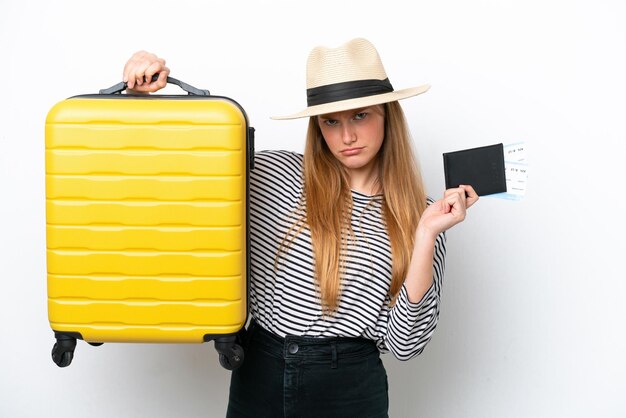 Foto jovem mulher caucasiana isolada no fundo branco infeliz nas férias com mala e passaporte