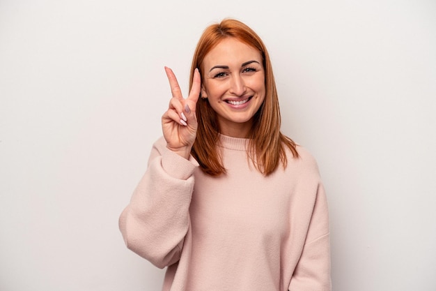 Jovem mulher caucasiana isolada no fundo branco, mostrando o número dois com os dedos.