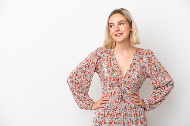 Jovem mulher caucasiana, isolada no fundo branco, posando com os braços na cintura e sorrindo