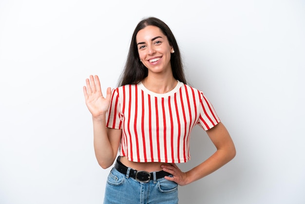 Jovem mulher caucasiana isolada no fundo branco saudando com a mão com expressão feliz