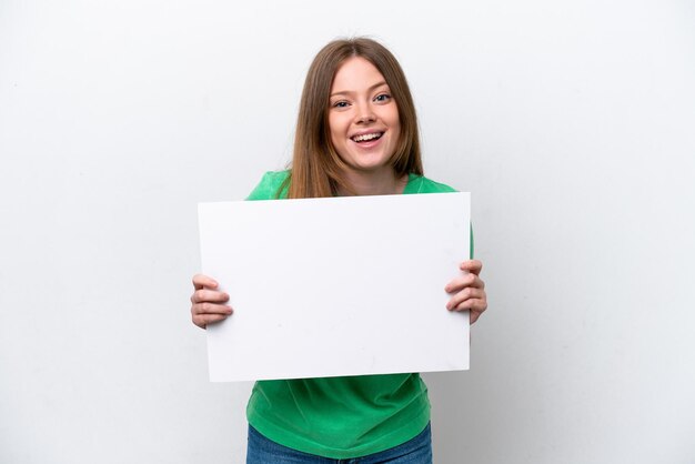 Jovem mulher caucasiana isolada no fundo branco segurando um cartaz vazio com expressão feliz