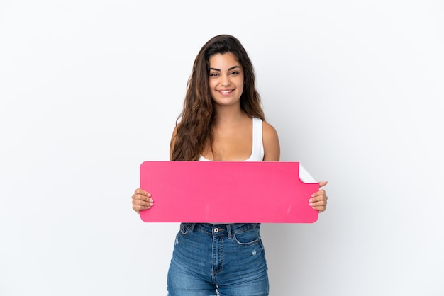 Jovem mulher caucasiana isolada no fundo branco segurando um cartaz vazio