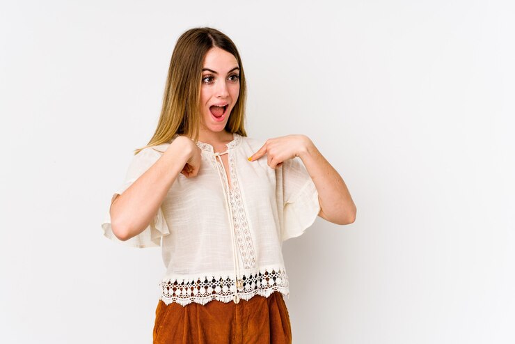 Foto jovem mulher caucasiana isolada no fundo branco surpreendeu apontando com o dedo, sorrindo amplamente.