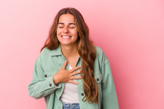 Jovem mulher caucasiana isolada no fundo rosa rindo mantendo as mãos no coração, o conceito de felicidade.