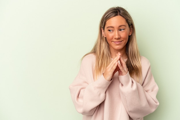 Jovem mulher caucasiana isolada sobre fundo verde, fazendo um plano em mente, estabelecendo uma ideia.