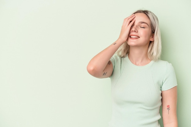 Jovem mulher caucasiana isolada sobre fundo verde, rindo de emoção feliz, despreocupada e natural.