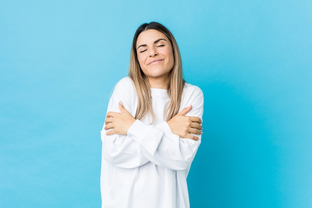 Jovem mulher caucasiana isolado abraços, sorrindo despreocupado e feliz.