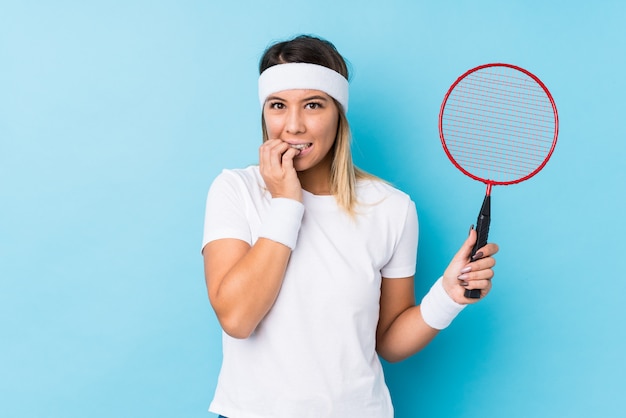 Jovem mulher caucasiana jogando badminton isolado unhas cortantes, nervosas e muito ansiosas.