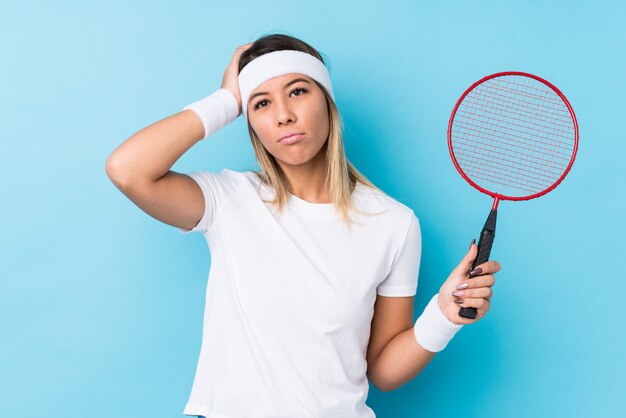 Jovem mulher caucasiana jogando badminton sendo chocado, ela se lembrou de uma reunião importante.