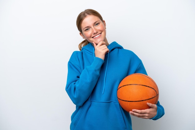 Jovem mulher caucasiana jogando basquete isolada no fundo branco feliz e sorridente
