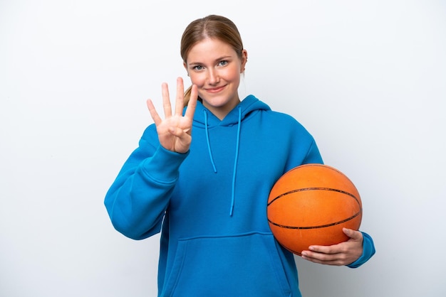 Jovem mulher caucasiana jogando basquete isolado no fundo branco feliz e contando quatro com os dedos