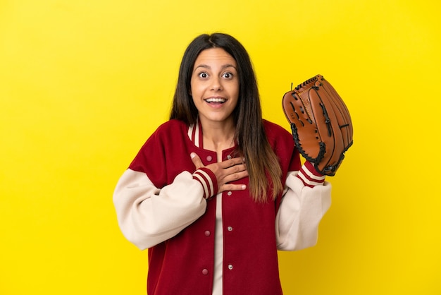 Jovem mulher caucasiana jogando beisebol isolada em um fundo amarelo surpresa e chocada ao olhar para a direita