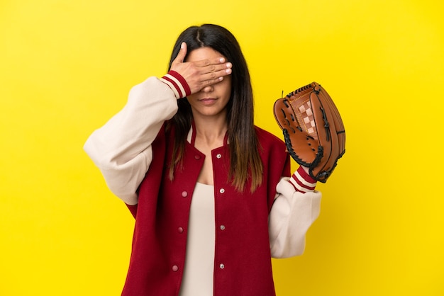 Jovem mulher caucasiana jogando beisebol isolado em um fundo amarelo, cobrindo os olhos com as mãos. Não quero ver nada