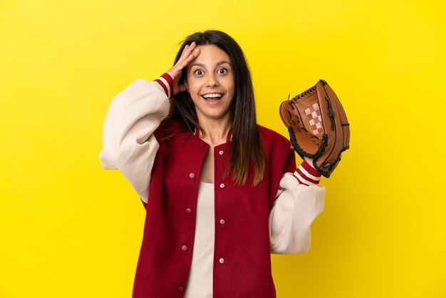 Jovem mulher caucasiana jogando beisebol isolado em um fundo amarelo com expressão de surpresa