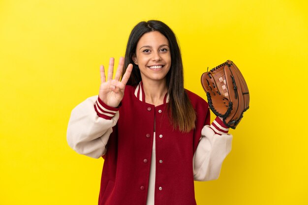 Jovem mulher caucasiana jogando beisebol isolado em um fundo amarelo feliz e contando quatro com os dedos