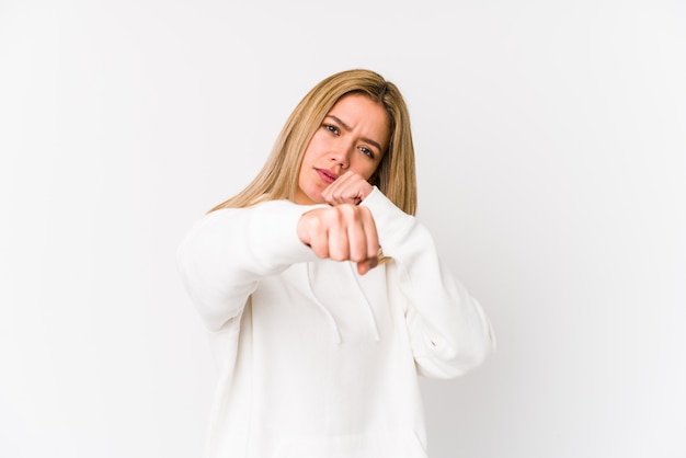 Jovem mulher caucasiana loira isolada jogando um soco, raiva, lutando devido a uma discussão, boxe.