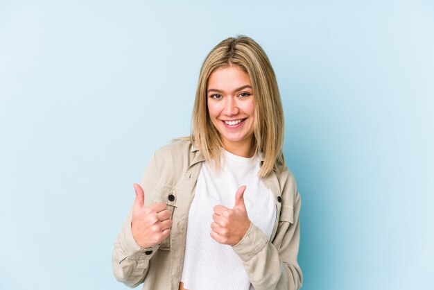 Jovem mulher caucasiana loira isolada levantando os dois polegares, sorrindo e confiante.