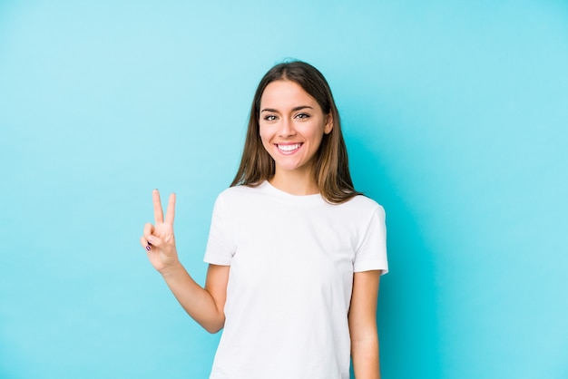 Jovem mulher caucasiana, mostrando o número dois com os dedos.