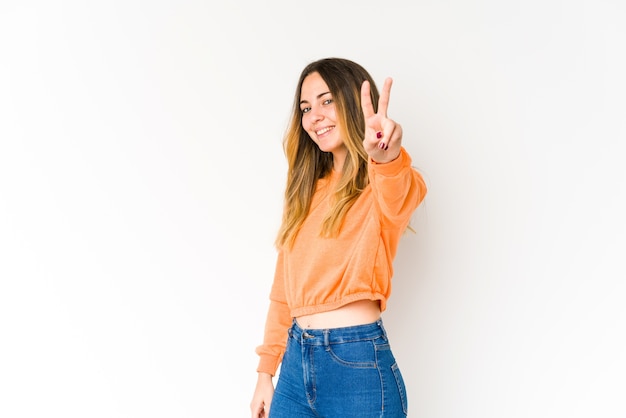 Jovem mulher caucasiana, mostrando sinal de vitória e sorrindo amplamente.