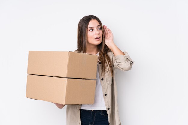 Jovem mulher caucasiana, movendo-se para uma nova casa, tentando ouvir uma fofoca.