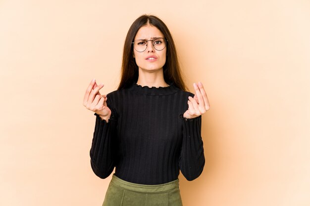 Jovem mulher caucasiana na parede bege, mostrando que ela não tem dinheiro.