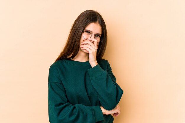 Jovem mulher caucasiana na parede bege rindo emoção feliz, despreocupada, natural.