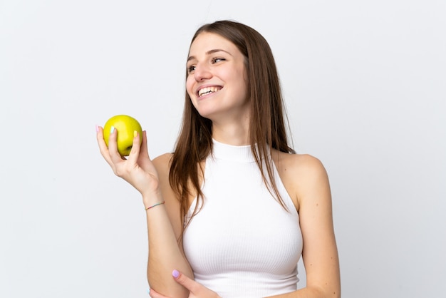 Jovem mulher caucasiana na parede branca com uma maçã e feliz