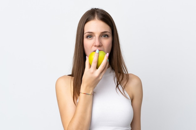 Jovem mulher caucasiana na parede branca, comendo uma maçã