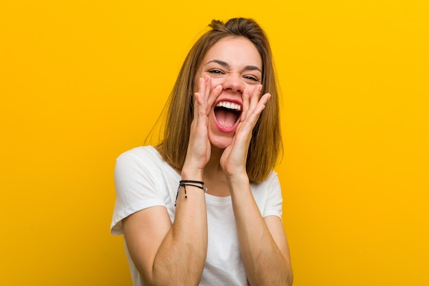 Jovem mulher caucasiana natural gritando animado para a frente.