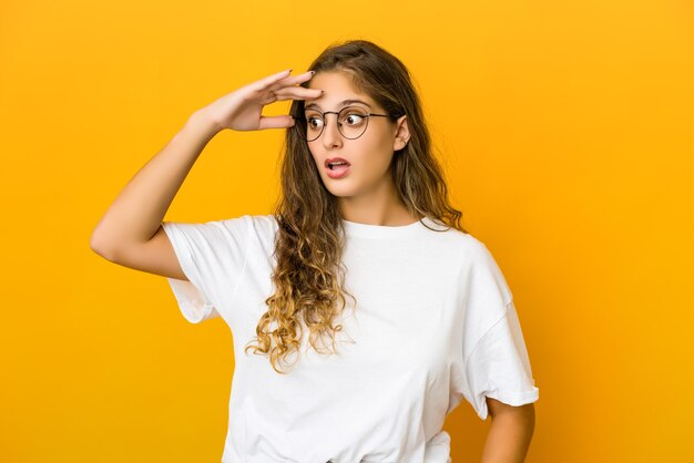 Jovem mulher caucasiana, olhando para longe, mantendo a mão na testa.