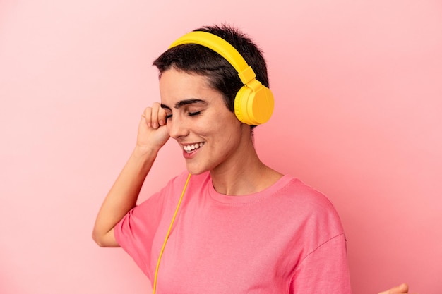 Jovem mulher caucasiana ouvindo música isolada em um fundo rosa