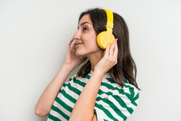 Jovem mulher caucasiana ouvindo música isolada no fundo branco