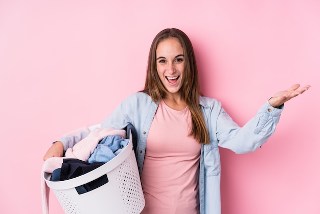 Jovem mulher caucasiana, pegar a roupa suja isolada recebendo uma surpresa agradável, animada e levantando as mãos.