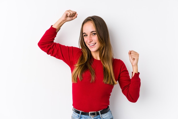 Jovem mulher caucasiana posando isolada comemorando um dia especial, pula e levanta os braços com energia.