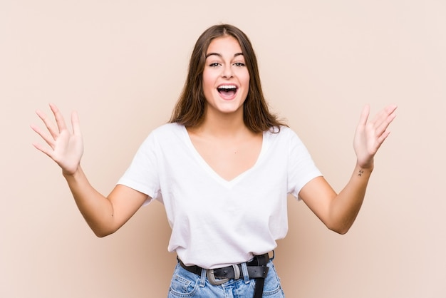 Jovem mulher caucasiana posando isolada recebendo uma agradável surpresa, animada e levantando as mãos.