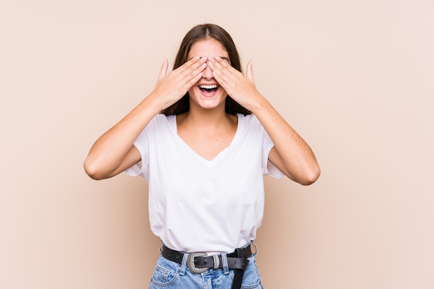 Foto jovem mulher caucasiana posando isolado cobre os olhos com as mãos, sorri amplamente esperando por uma surpresa.