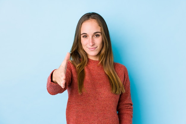 Jovem mulher caucasiana posando isolado esticando a mão no gesto de saudação.