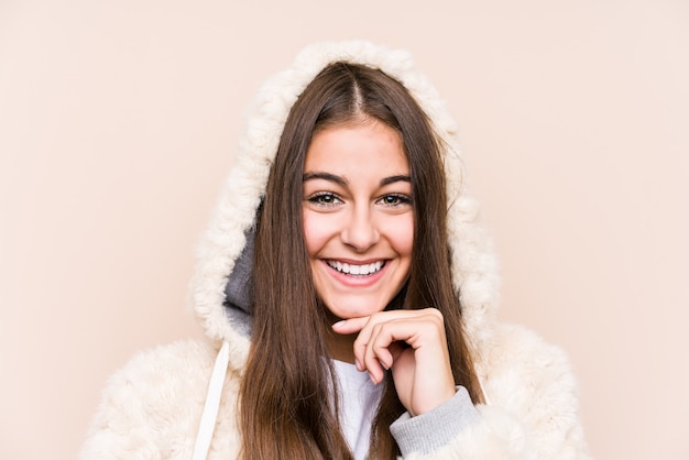 Jovem mulher caucasiana posando isolado sorrindo feliz e confiante, tocando o queixo com a mão.