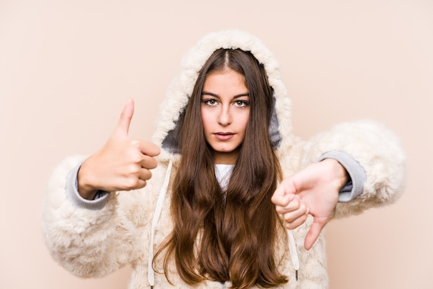 Jovem mulher caucasiana posando mostrando os polegares para cima e os polegares para baixo